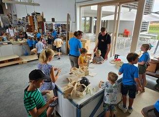 Kinder und Tischler arbeiten gemeinsam an Holz Ferienspass in deiner Traditionstischlerei