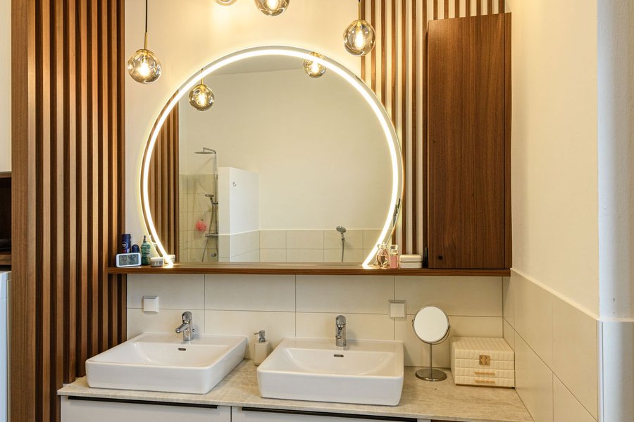 © Wolfgang Stecher/grapple.at Badezimmer mit zwei Waschbecken, einem großen Spiegel und einer Holzlamellenwand als Abtrennung