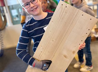 Kind mit einem großen Stück Holz Handwerklicher Besuch der Volksschule Hafnerbach