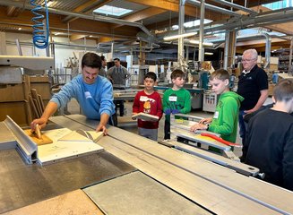 Kinder sehen beim Bearbeiten von Holz zu Handwerklicher Besuch der Volksschule Hafnerbach