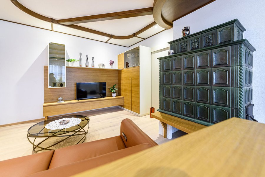 © Wolfgang Stecher/grapple.at Wohnzimmer mit Wohnzimmerwandverbau aus Holz und grünem alten Kachelofen