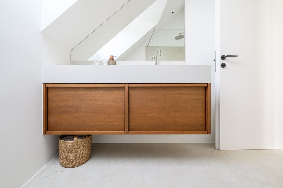 © Wolfgang Stecher/grapple.at Moderner Badezimmerschrank in Holz mit aufgesetzten Waschbecken und einem großen Spiegel im Hintergrund.
