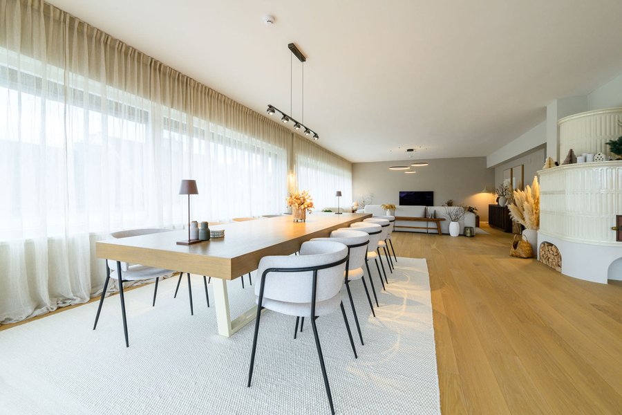 Wohnbereich mit großem Tisch und weißen Sesseln auf einem großen weißen Teppich und einer schwarzen modernen Lampe