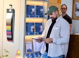 Gast beim Stöbern durch Werbematerialien Grenzenloser Architektenabend