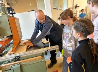 Kinder schauen Tischlermeister beim Arbeiten mit Holz über die Schulter Handwerklicher Besuch der Volksschule Hafnerbach
