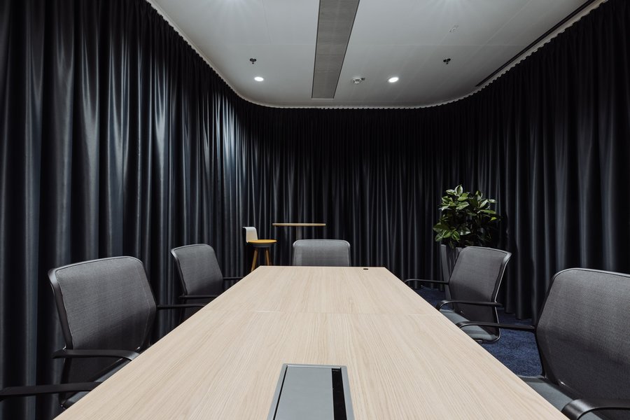 Großer Besprechungsraum mit Tisch und Sesseln sowie mit schwarzen Vorhängen zum Verdunkeln