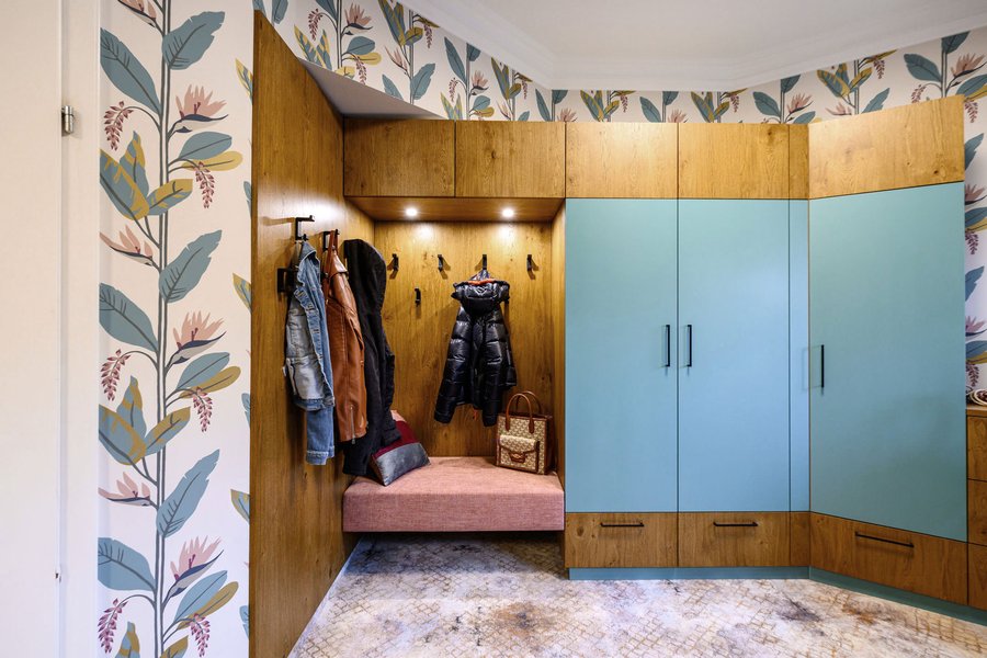 Vorraum mit Blumentapete und braun türkisen Möbeln und einer Garderobe mit Jacken