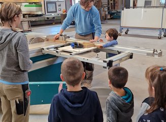 Mitarbeiter:innen der Tischlerei Krumböck schneiden mit den Kindern gemeinsam Holz Kindergarten Gerersdorf zu Besuch