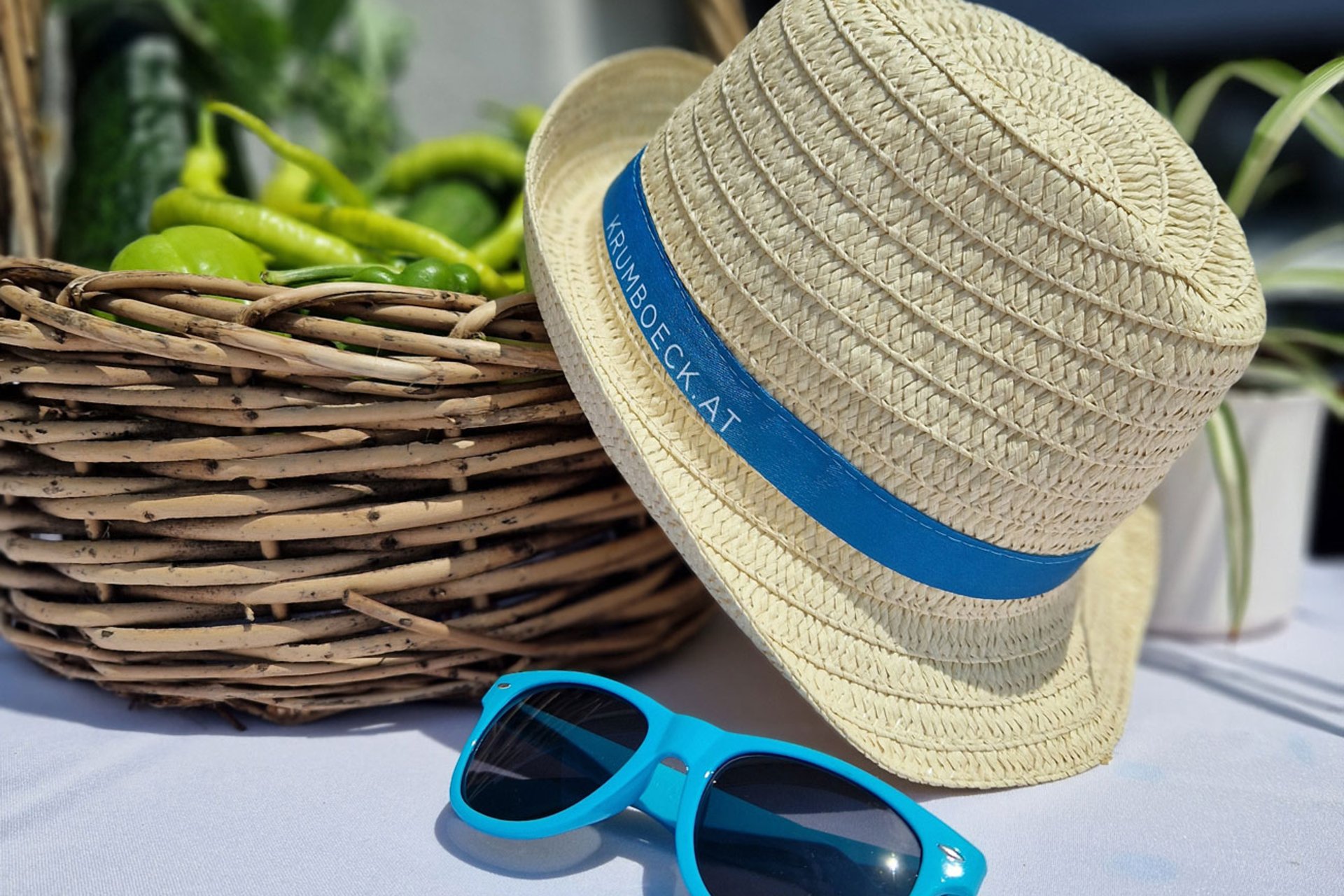 Sommerhut und Sonnenbrille liegen auf einem weißen Tisch