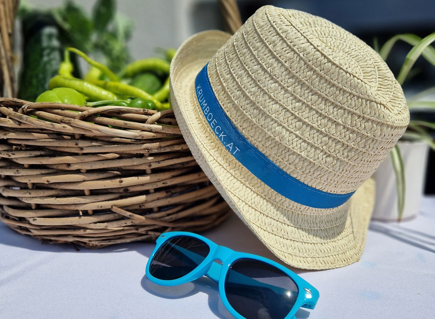 Sommerhut und Sonnenbrille liegen auf einem weißen Tisch