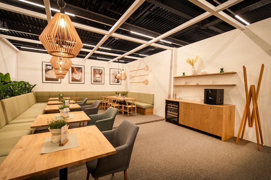 © Stefan Knittl Innenraum eines Messestandes mit Tischen und Sesseln