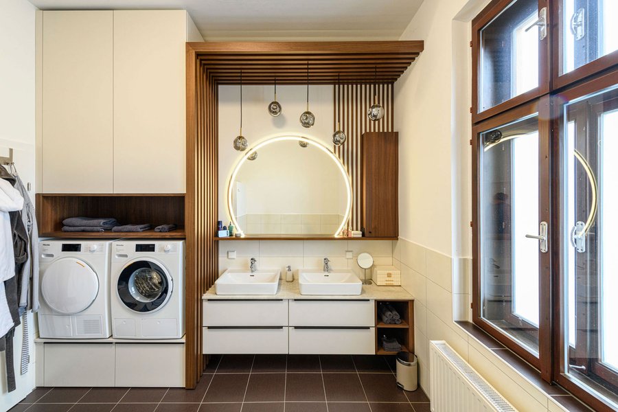 © Wolfgang Stecher/grapple.at Badezimmer mit zwei Waschbecken, einem Waschmaschinenverbau und einer Holzlamellenwand
