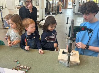 Mitarbeiter der Tischlerei erklärt Kindern Holzbearbeitung Kindergarten Gerersdorf zu Besuch