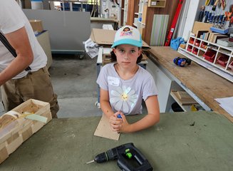 Kind in der Werkstatt einer Tischlerei beim Bearbeiten von Holz Ferienspass in deiner Traditionstischlerei