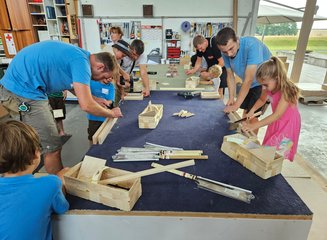 Kinder arbeiten an einer Werkbank in einer Tischlerei an kleinen Holzstücken Ferienspass in deiner Traditionstischlerei
