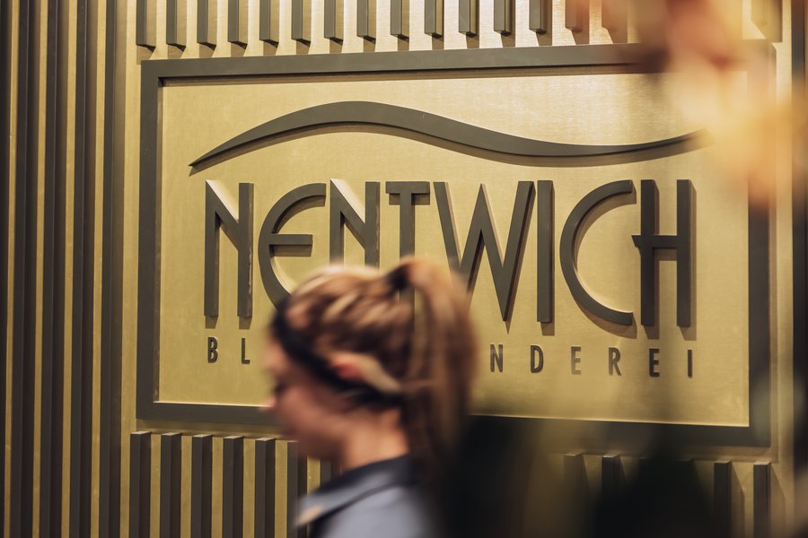 Detailaufnahme von Logo der Firma Nentwich mit Mitarbeiterin im Vordergrund