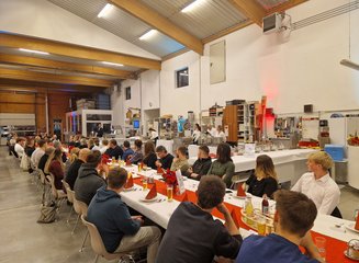 Mitarbeiter an der großen Tafel hören der Geschäftsleitung bei der Ansprache zu Weihnachtsfeier 2024