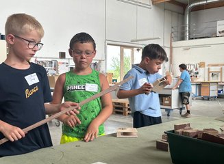 Kinder beim Arbeiten mit Holz in einer Tischlerei Ferienspass 2026: Kleine Werkstücke, große Begeisterung