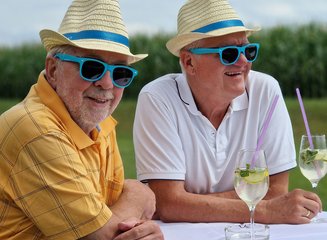 Senirochef mit einem Mitarbeiter an einem Stehtisch mit zwei Getränken am Tisch Sommerfest 2025