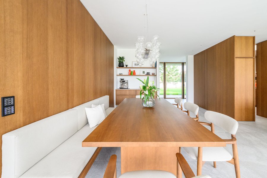 © Wolfgang Stecher/grapple.at Moderne Esszimmeransicht mit einem langen Holztisch, weißen Stühlen und einer eleganten Deckenlampe.