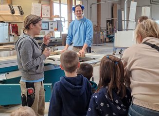Mitarbeiter:innen der Tischlerei Krumböck erklären Kindern die Bearbeitungsmaschinen Kindergarten Gerersdorf zu Besuch