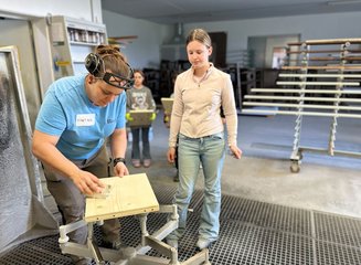 Mitarbeiterin einer Tischlerei beim Schleifen von Holz Handwerklicher Besuch der Volksschule Hafnerbach