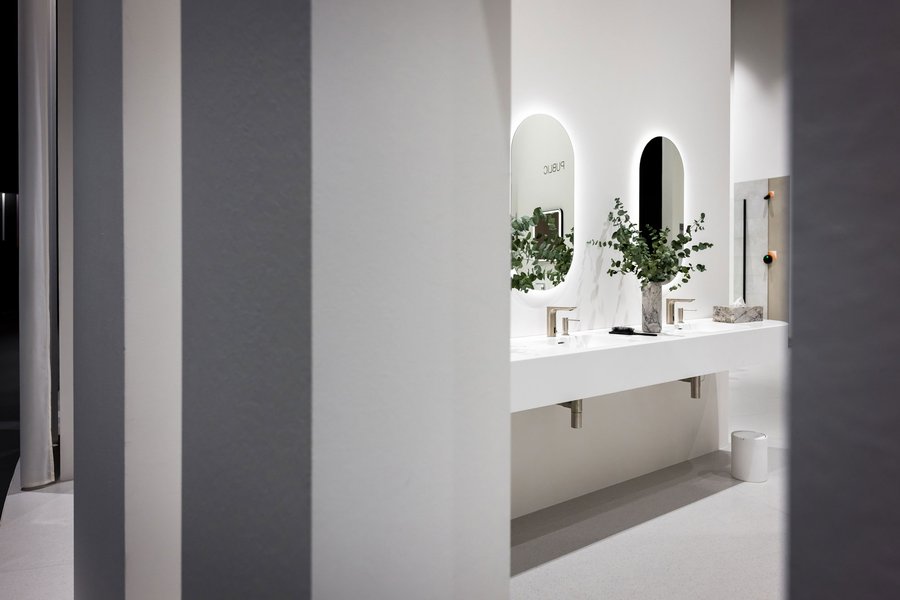 © Kim Culetto Waschbecken in weiß mit Spiegel an der Wand auf einem Messestand