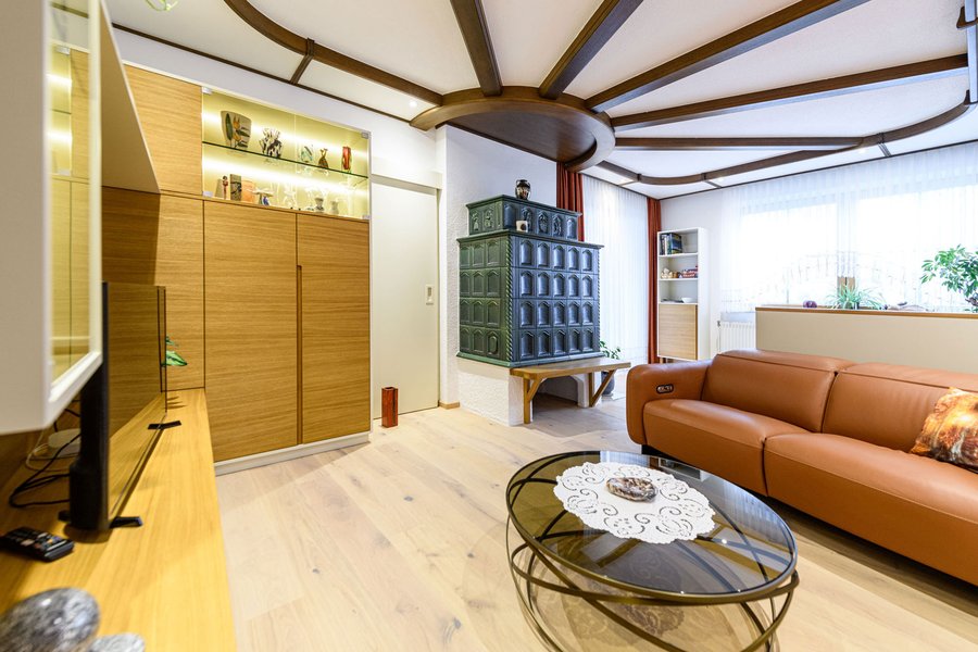 © Wolfgang Stecher/grapple.at Wohnzimmerschränke aus Holz mit Couch und grünem Kachelofen