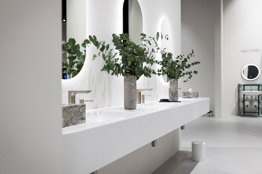 © Kim Culetto Waschbecken in weiß mit Vasen und Pflanzen sowie beleuchteten Spiegeln