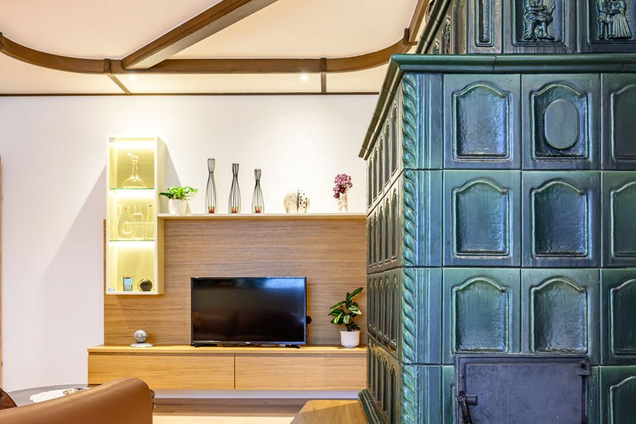 © Wolfgang Stecher/grapple.at Grüner Kachelofen im Wohnzimmer mti Blick auf den Wohnzimmerverbau inklusive TV