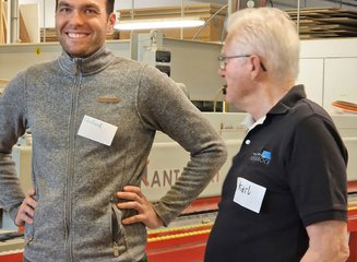 zwei Personen unterhalten sich in einer Tischlerei Handwerklicher Besuch der Volksschule Hafnerbach