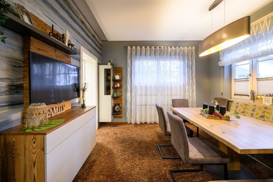 Esszimmer mit großem Tisch und einem Regal mit Fernseher