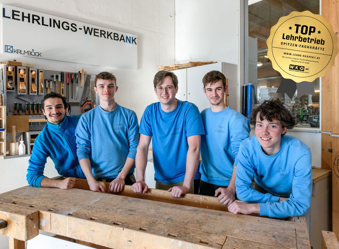 Fünf männliche Lehrlinge bei einer Werkbank in der Tischlerei