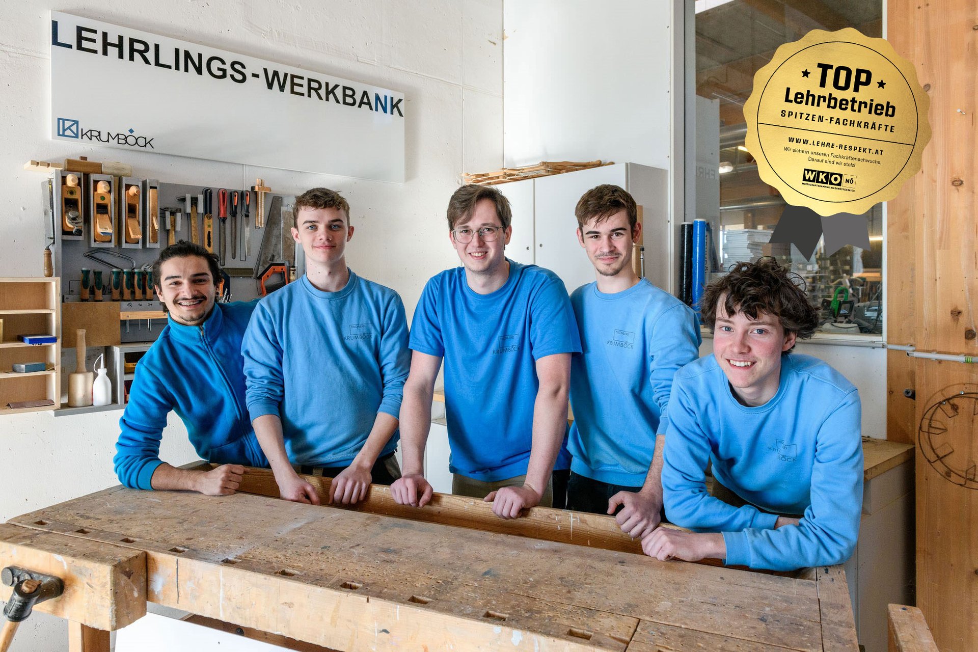 Fünf männliche Lehrlinge bei einer Werkbank in der Tischlerei